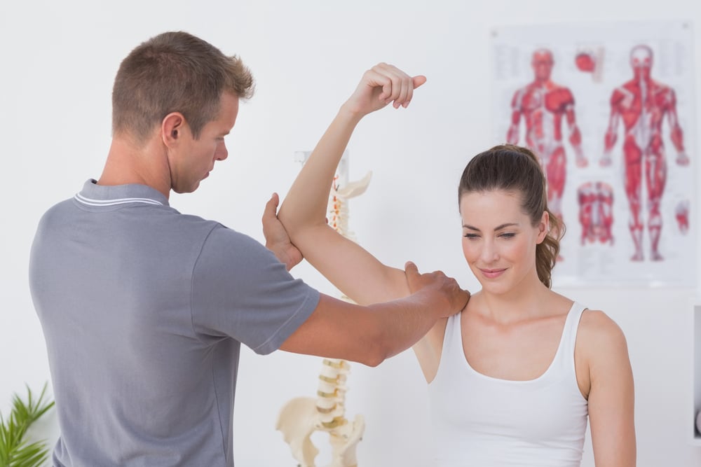 Doctor stretching a young woman arm in medical office